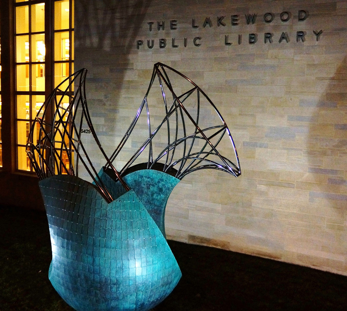 Transversion at night a  bronze and stainless public sculpture by Peter Diepenbrock Lakewood Ohio